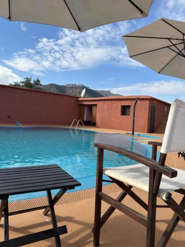 a chair and an umbrella next to a swimming pool at atlas lodge in Amizmiz