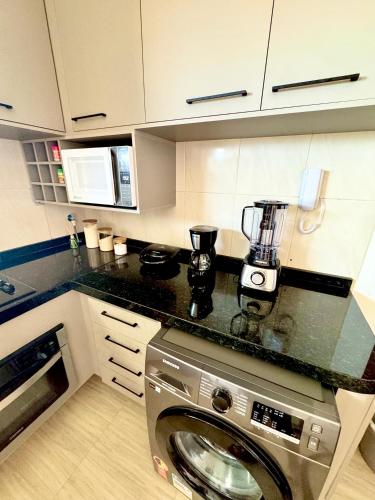 a kitchen with a washing machine in a kitchen at Apartamento Beach place Cumbuco 100m da Praia in Caucaia