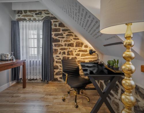 an attic office with a desk and a stone wall at Hôtel Maison Otis in Baie-Saint-Paul