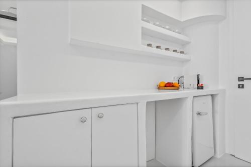 a white kitchen with white cabinets and a bowl of fruit at Heart of Mykonos Suites in Mýkonos City