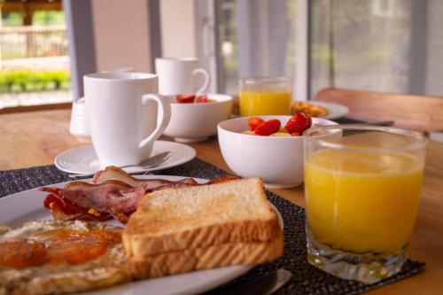 a table with a plate of breakfast food and orange juice at chez Yannick Hospedaje Los Amigos in Salento