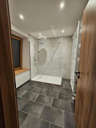 a bathroom with a shower and a tiled floor at L'Escargot - Maison avec espace bien être in Vagney