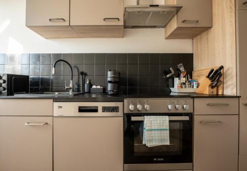 a kitchen with white cabinets and a black oven at Airport Apartment für 4 - Smart TV - Küche - eCharger in Hamburg