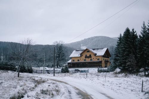 a house on a snow covered road next to a snow covered field at La Lacuri in Sovata