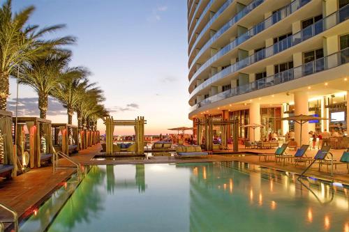 a hotel swimming pool with palm trees and a building at Stunning Beachfront 3-Bedroom Corner Residence in Hollywood