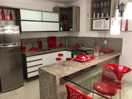 a kitchen with a counter and red chairs in it at HOTEL CANARIUS DE GRAVATA - Flat in Gravatá