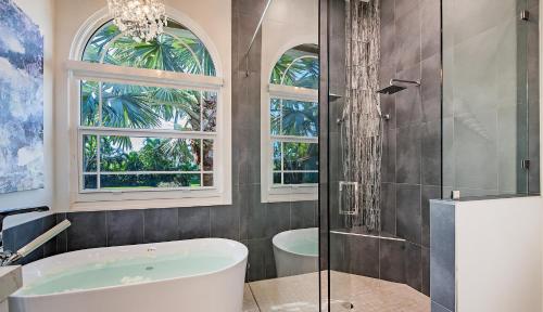 a bathroom with a tub and a glass shower at Canbiella in Marco Island