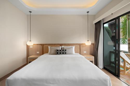 a bedroom with a white bed and a large window at Buasri Boutique Patong in Patong Beach