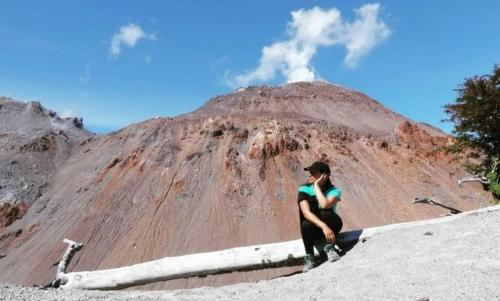 a woman sitting on the side of a dirt hill at Fío Fío Patagonia in Chaitén