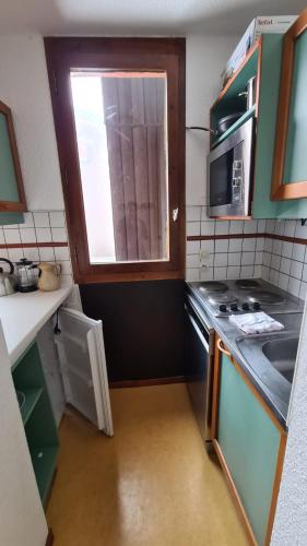 Il comprend une petite cuisine avec une cuisinière et une fenêtre. dans l'établissement Belle-Plagne, skis aux pieds, à La Plagne Tarentaise