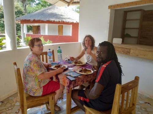 a group of people sitting at a table eating food at Campement les Antilles in Abene