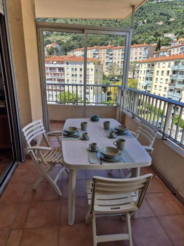 une table blanche et des chaises sur un balcon dans l'établissement Apartment 6 minutes from Monaco train station, à Beausoleil