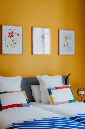 a bedroom with yellow walls and a bed with pillows at L'appartement - Meursault in Meursault