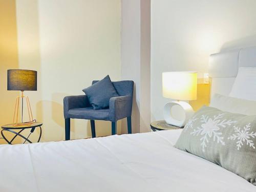 a bedroom with a bed and a blue chair at Les Marmottes by valcenis net in Val Cenis