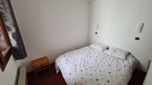 une petite chambre avec un lit et une table de chevet dans l'établissement Belle-Plagne, skis aux pieds, à La Plagne Tarentaise
