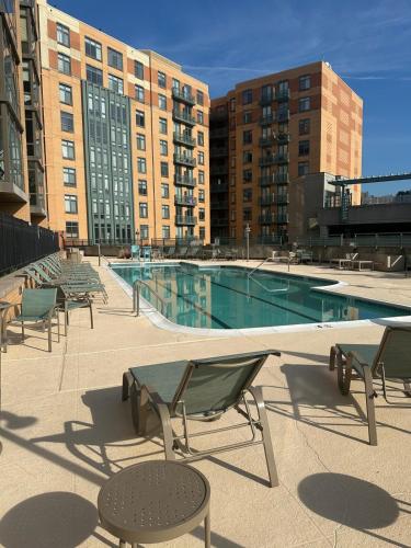 a pool with chairs and a table and some buildings at Beautiful Arlington Apartment with Pool & Parking! in Arlington