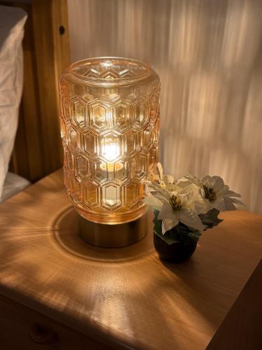 a clear glass vase sitting on a table with flowers at 2 Bedroom House in Nottingham