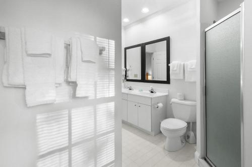 a white bathroom with a toilet and a mirror at Pawleys Plantation Retreat Villa Deluxe Amenities in Pawleys Island