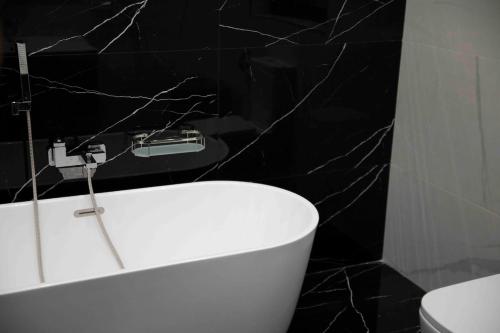 a bathroom with a white tub and a black wall at Flat 3, nearby Beaches & Countryside, with Terrace in Mġarr
