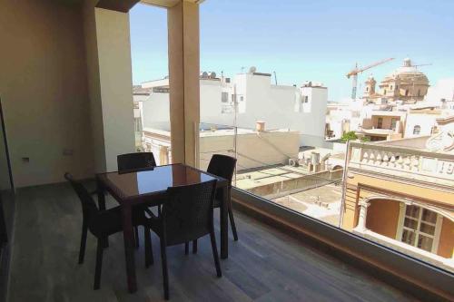 a dining room with a table and chairs and a large window at Flat 3, nearby Beaches & Countryside, with Terrace in Mġarr
