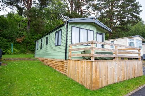 una piccola casa verde in cima a una recinzione di legno di Grantown Getaway - SJA Stays - Modern 2 Bed Static a Grantown on Spey