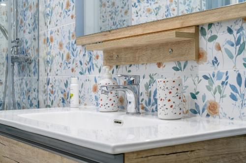 a white sink in a bathroom with floral wallpaper at "A casa dei Nonni" House near the metro C in Rome