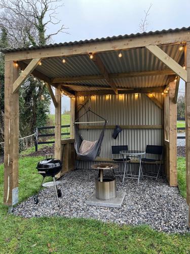 a patio with a hammock and a table and a grill at Riverside Retreat in Monaghan