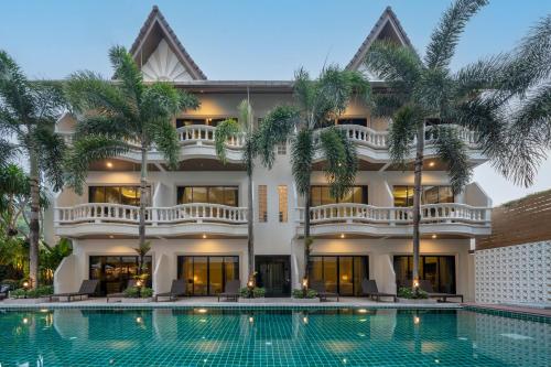 a villa with a swimming pool in front of a building at Buasri Boutique Patong in Patong Beach