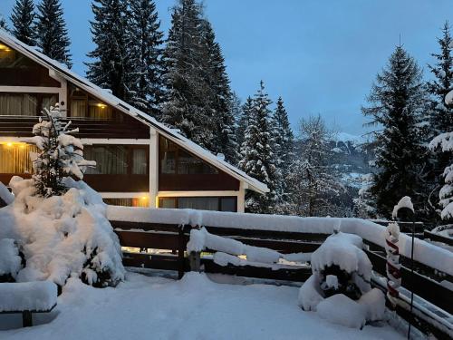 dom pokryty śniegiem obok płotu w obiekcie Casetta dei Cuori - Alpine Style Cozy Apartment w mieście Folgarida