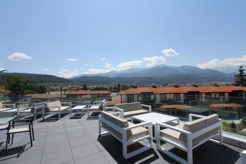 a group of chairs and tables on a patio with mountains at Ruskovets Thermal SPA & Ski Resort in Bansko