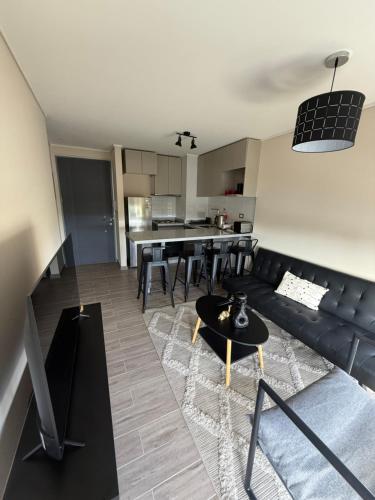 a living room with a black couch and a table at Depto Claudio 904 in Chillán