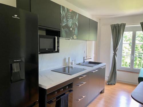 une cuisine avec un évier et un micro-ondes dans l'établissement Appartement, tout confort, à Veigné