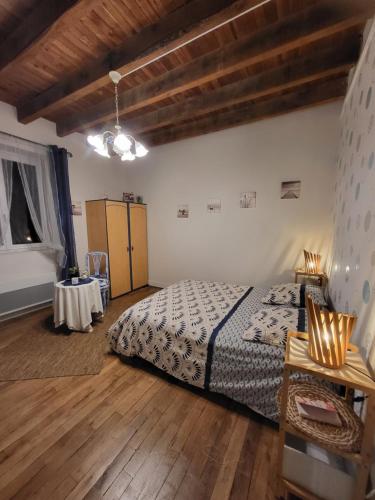 Un dormitorio con una cama y una mesa dentro. en Au doux refuge, en Saint-Exupéry-les-Roches