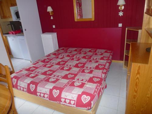 - une chambre dotée d'un lit avec un mur rouge dans l'établissement Valmorel La Belle, skis aux pieds!, à Valmorel