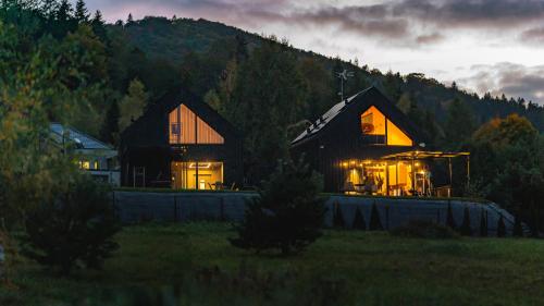 un paio di case in un campo di notte di Czarna Chata Luxury Resort a Klimkówka