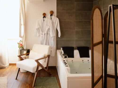 bagno con vasca, sedia e sedia di Suite Cara - Logement Atypique Sauna Balneo - Centre Historique a Brive-la-Gaillarde
