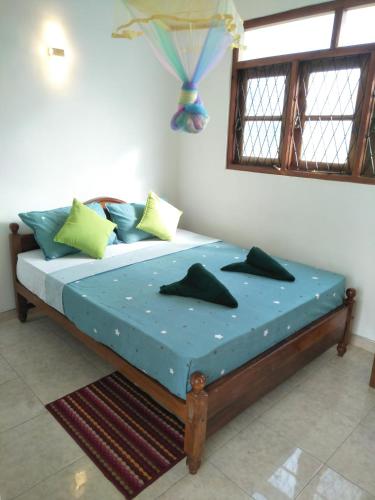 a bedroom with a bed with blue sheets and a window at Dickwella Green Villa in Dickwella