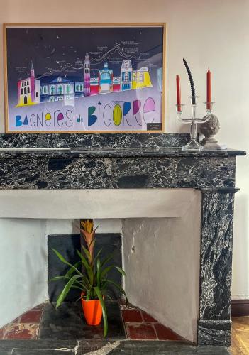 a fireplace with a painting above it with a plant at La Maison de Laulie in Bagnères-de-Bigorre