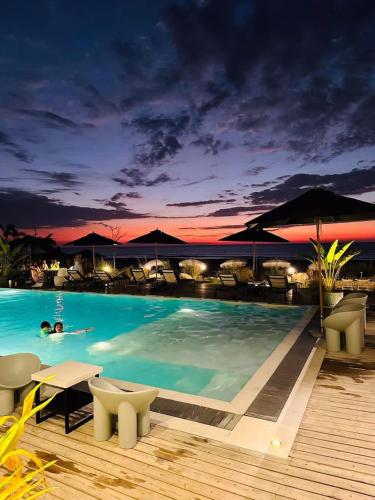 a pool with tables and chairs and a sunset at Natalna Boutique Home in Bacnotan