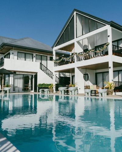 a hotel with a swimming pool in front of a building at Natalna Boutique Home in Bacnotan