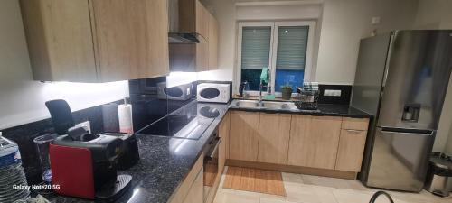 a kitchen with a sink and a refrigerator at Cocon tout confort bien situé in Saône