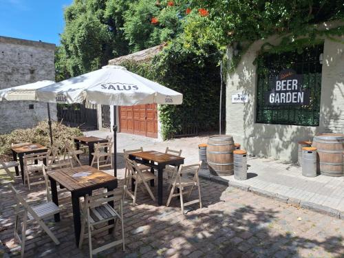 an outdoor patio with tables and chairs and an umbrella at Viajero Colonia Hostel in Colonia del Sacramento