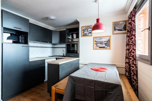 une cuisine avec des armoires noires et une table avec une plaque rouge. dans l'établissement Chalet Chamois - EN COMPLETE RENOVATION MAE-6361, à Val Thorens