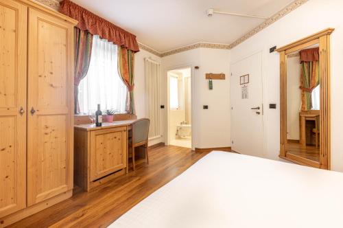 a bedroom with a bed and a desk and a window at Hotel Plank in San Martino di Castrozza