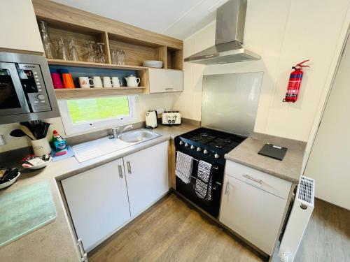 a small kitchen with a stove and a sink at 3 Bedroom Caravan OG35, Lower Hyde, Shanklin in Shanklin