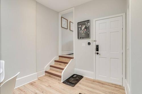 a white hallway with a white door and stairs at Casa Queen - Unique 2BR Suite in Leslieville in Toronto