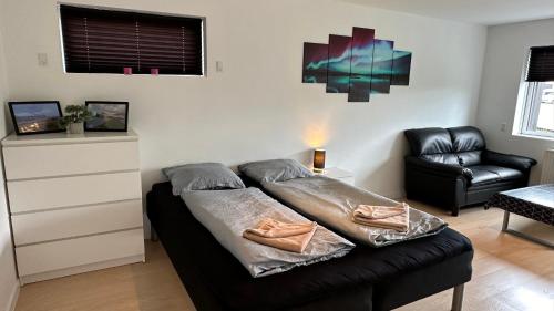 een woonkamer met een bed en een stoel bij Ingi's Guesthouse with a Car in Miðvágur