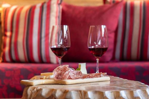 two glasses of red wine on a table with food at Hotel Plank in San Martino di Castrozza