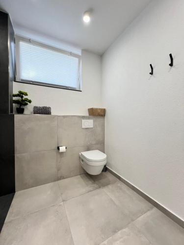 a bathroom with a toilet and a window at House of AlAy in Künzelsau