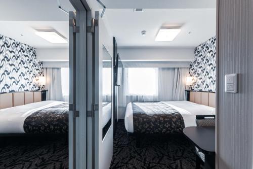 a hotel room with two beds and a window at APA Hotel & Resort Midosuji Hommachi Eki Tower in Osaka